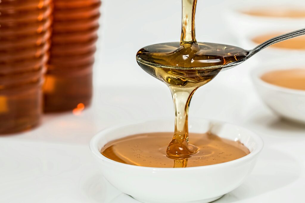 honey-sweet-syrup-organic-33260 Delicious honey pouring slowly from a spoon into a white bowl, highlighting its golden hue and viscosity.